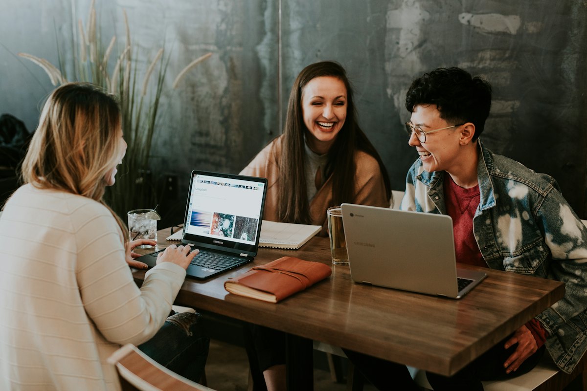 Three colleagues smiling while working on laptops