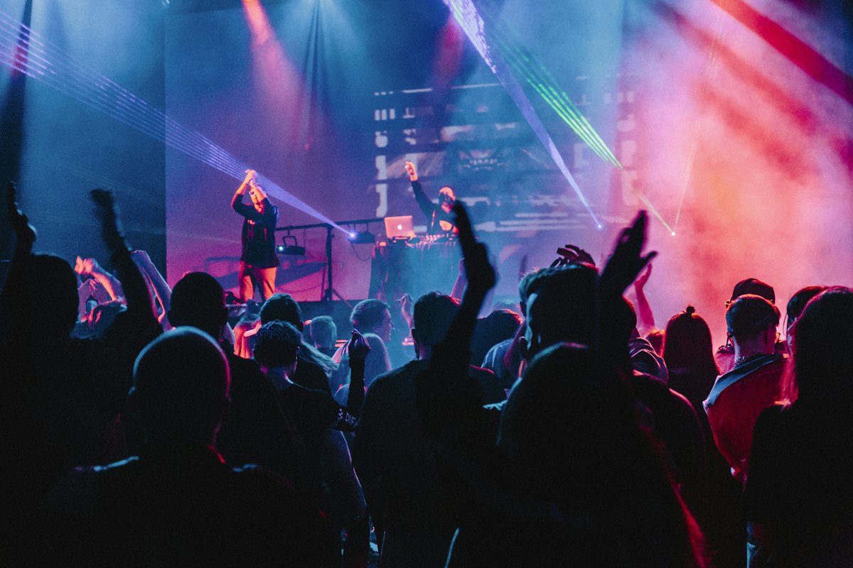 A concert crowd under purple and pink stage lighting