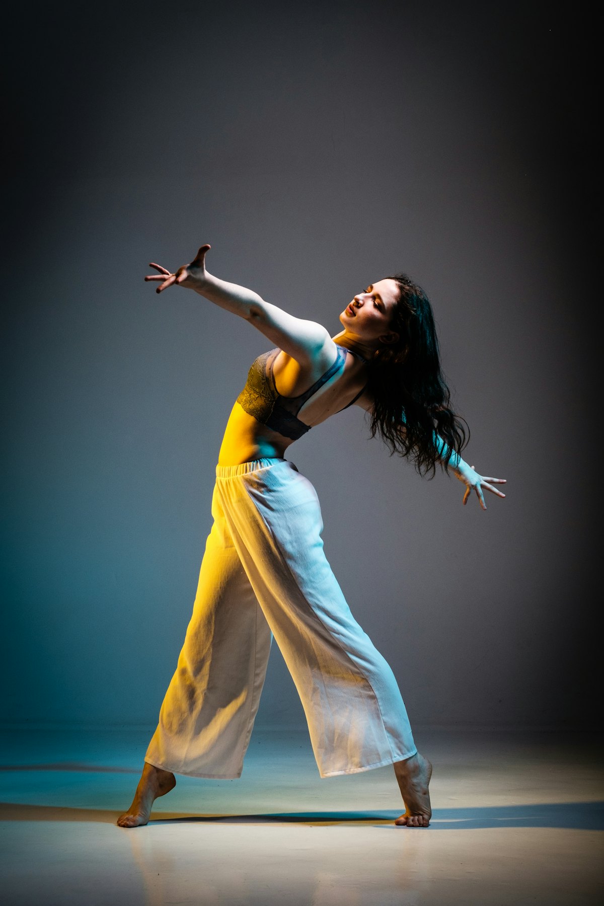 A dancer mid-movement against a grey backdrop